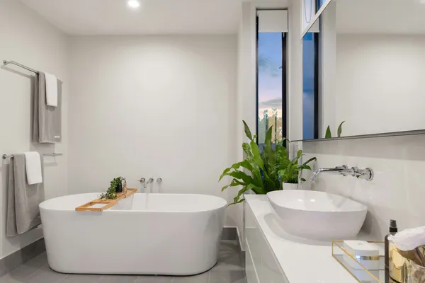 Banheiro branco com banheira e planta verde
