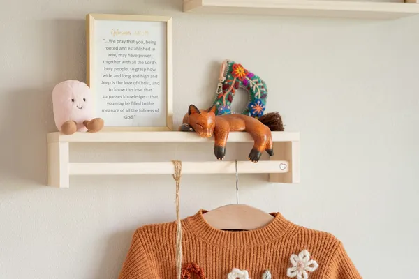 Prateleira infantil com brinquedos e casaquinho pendurado