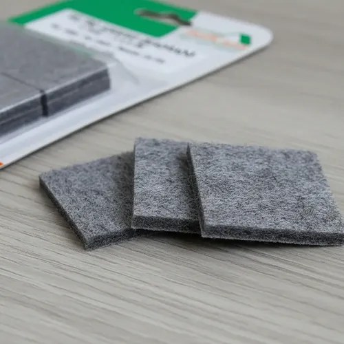 Feltros adesivos cinza quadrados sobre piso de madeira, foto do anúncio do produto no Mercado Livre