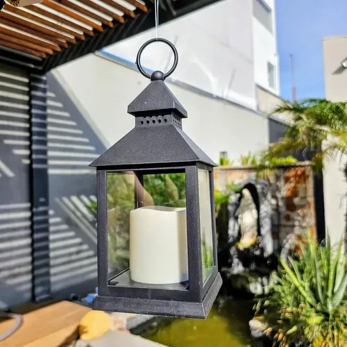 Lanterna preta com vela de LED pendurada em varanda com plantas, foto do anúncio do produto no Mercado Livre